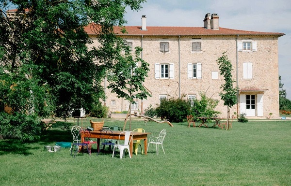 Photographie d'un château avec un jardin où sont installées tables et chaises